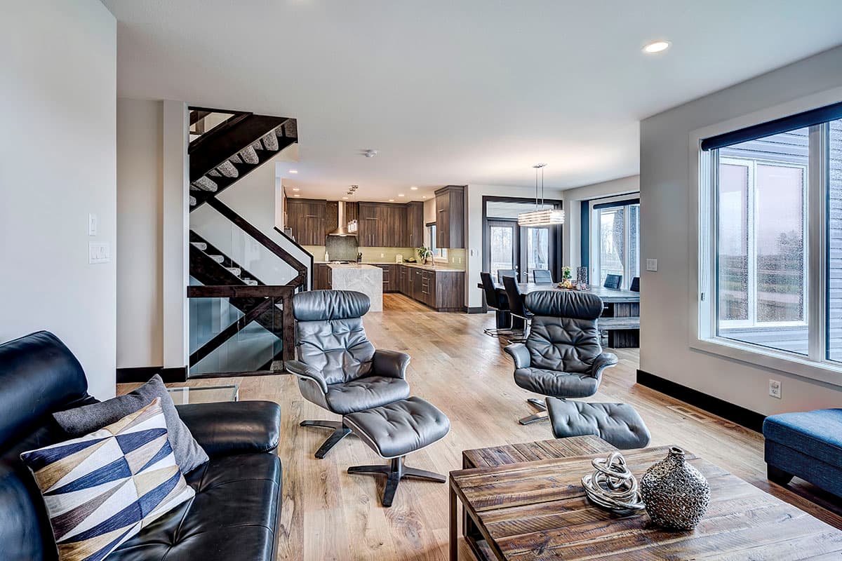 Open-concept living area with modern kitchen, dining area, and living room featuring a floating staircase.