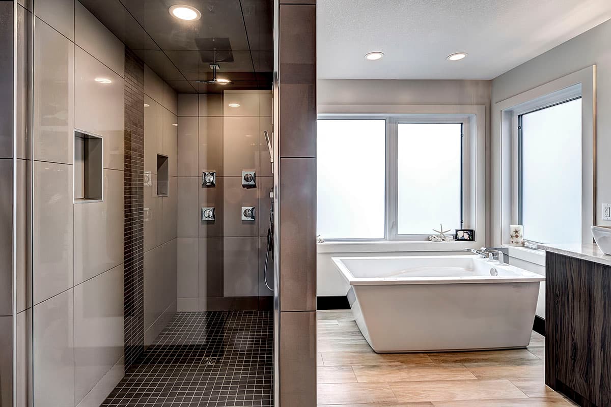 Contemporary bathroom with freestanding tub, multi-head shower enclosure, and large windows.