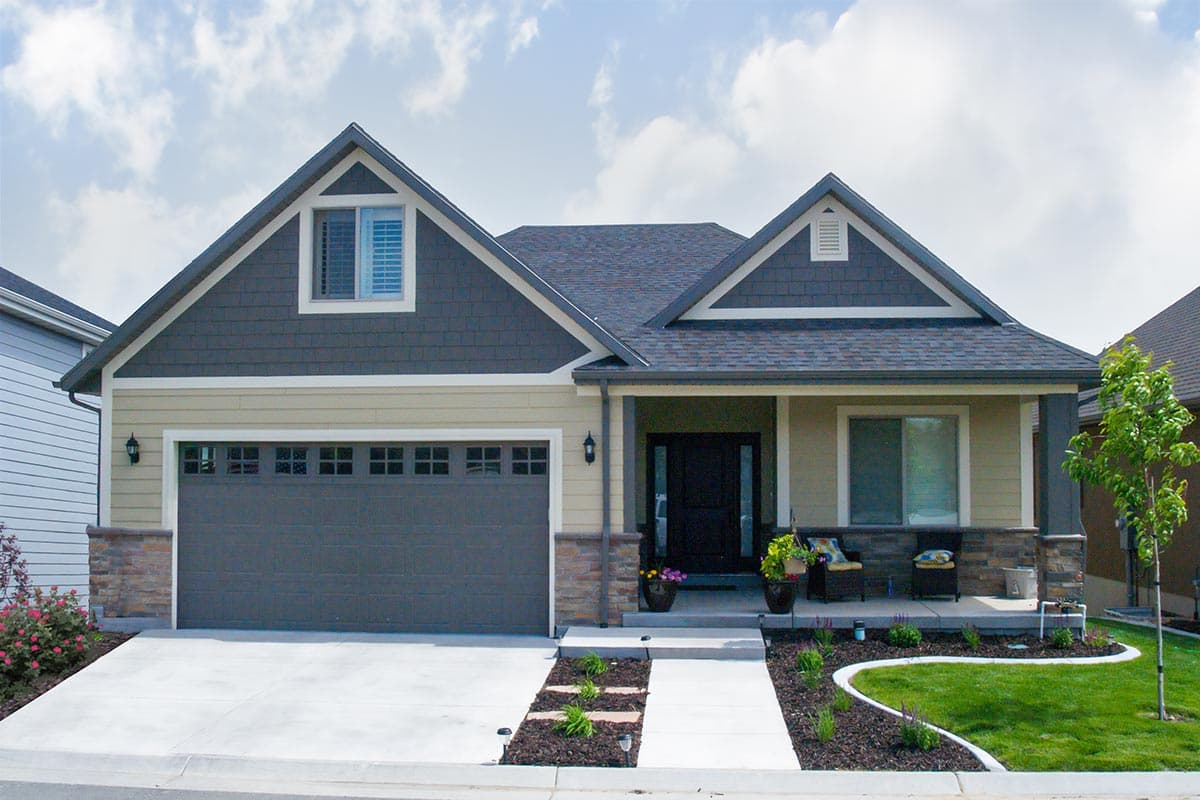 House plan exterior with Craftsman style. Features include a front-facing garage, gabled rooflines, and a covered porch with stone detailing.