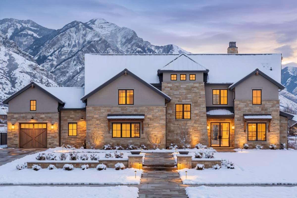 House plan exterior of a two-story home with stone accents, a prominent gable roof, and a three-car garage.