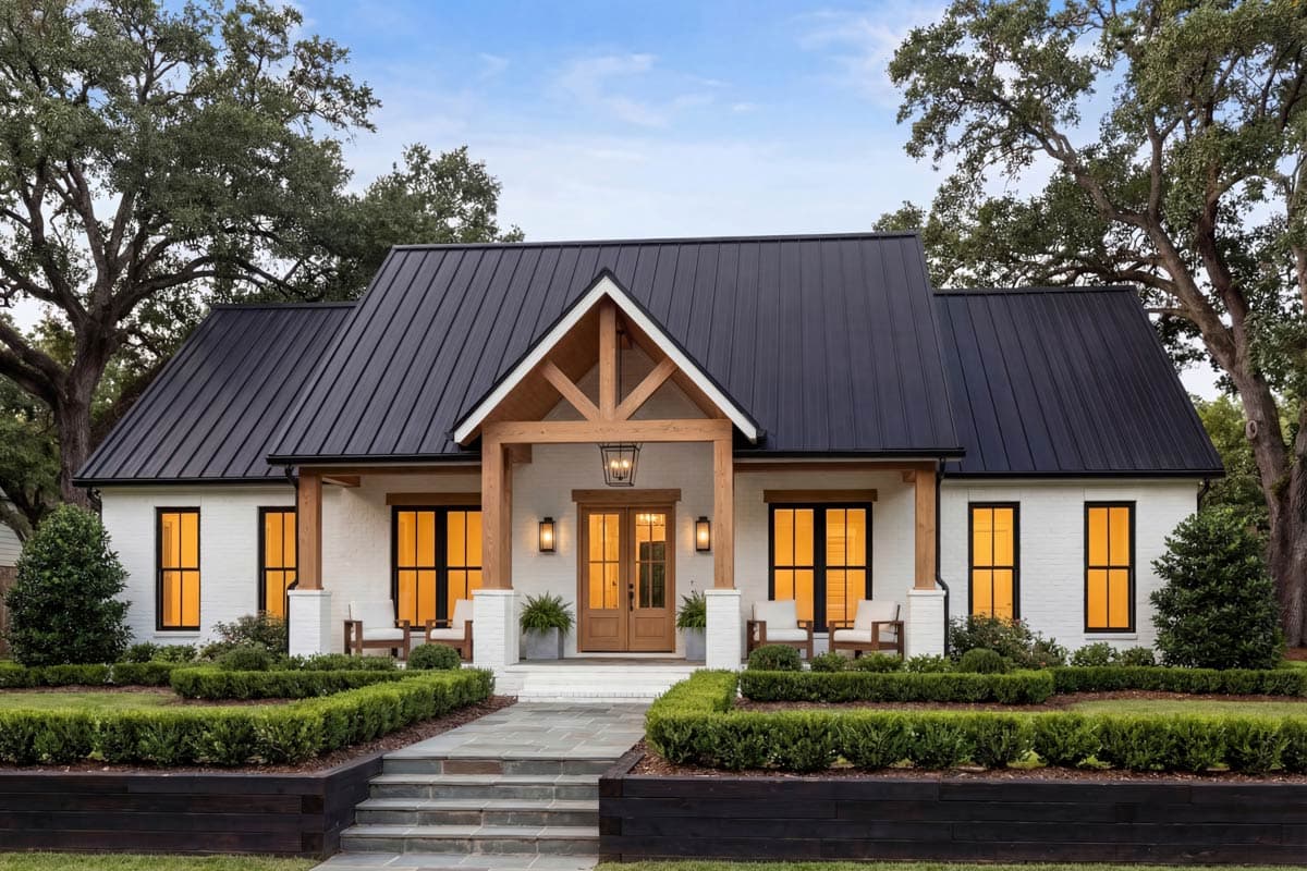 Modern Farmhouse exterior with white brick, black metal roof, exposed wood beams on front porch, and large black-framed windows.