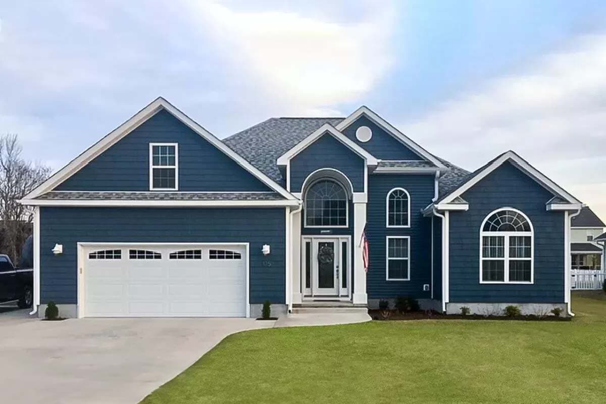 House plan exterior with two stories, gabled rooflines, arched entry window, and attached garage. Exterior features navy siding and white trim.