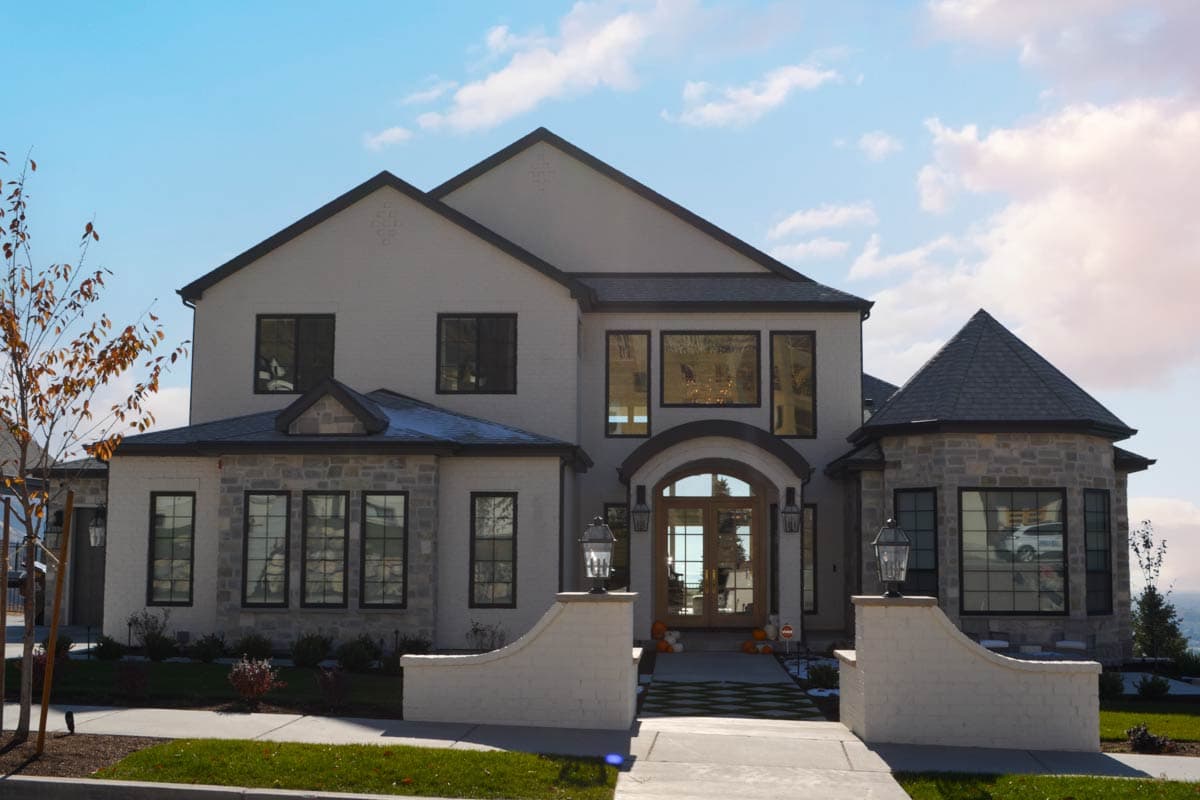 Two-story house plan exterior with stone accents, arched entry, and multi-level gabled rooflines.