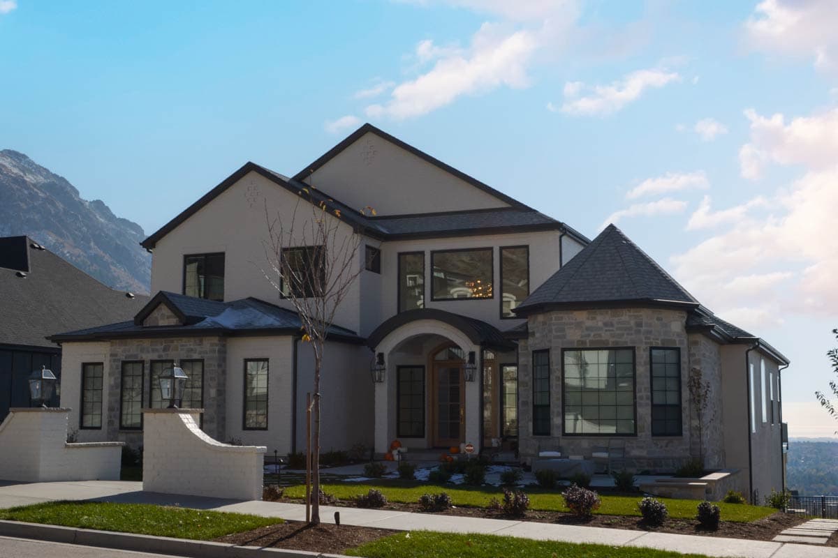 House plan exterior with stone turret, gabled rooflines, arched entryway, and multiple windows.