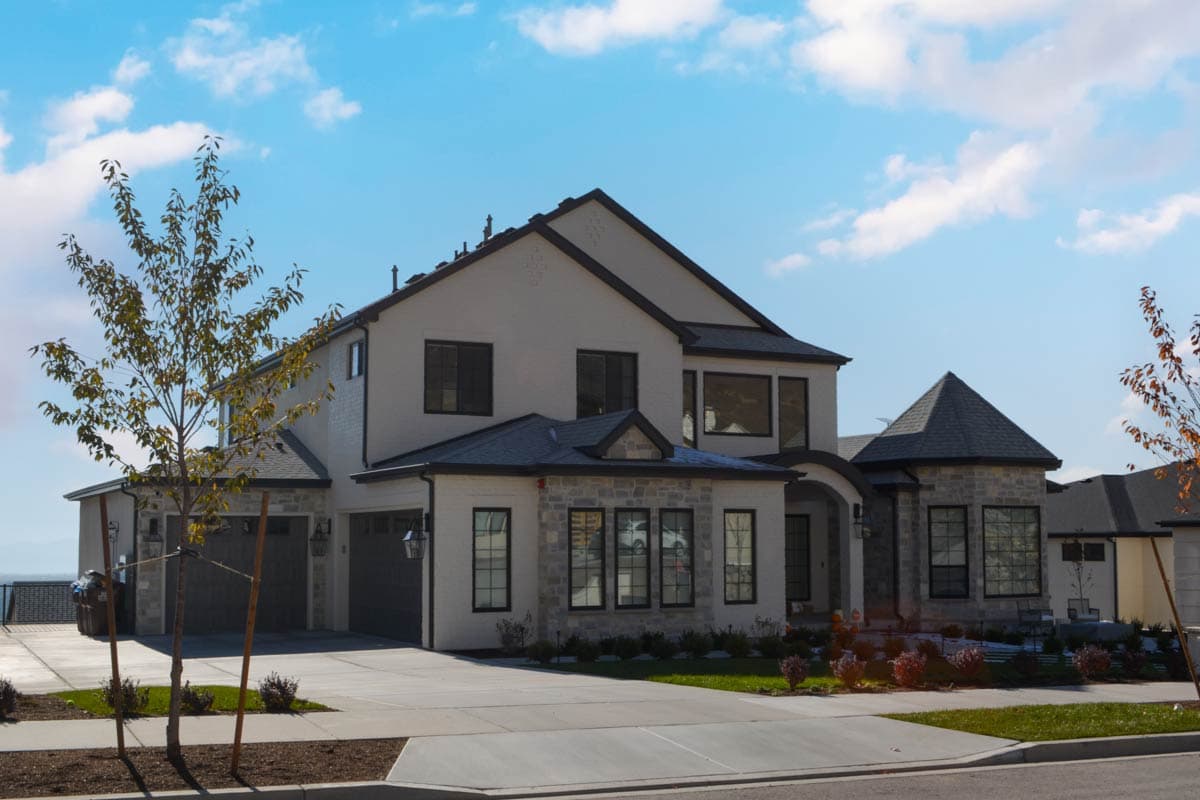 House plan exterior: Two-story home with stone accents, a prominent gable, and a three-car garage.