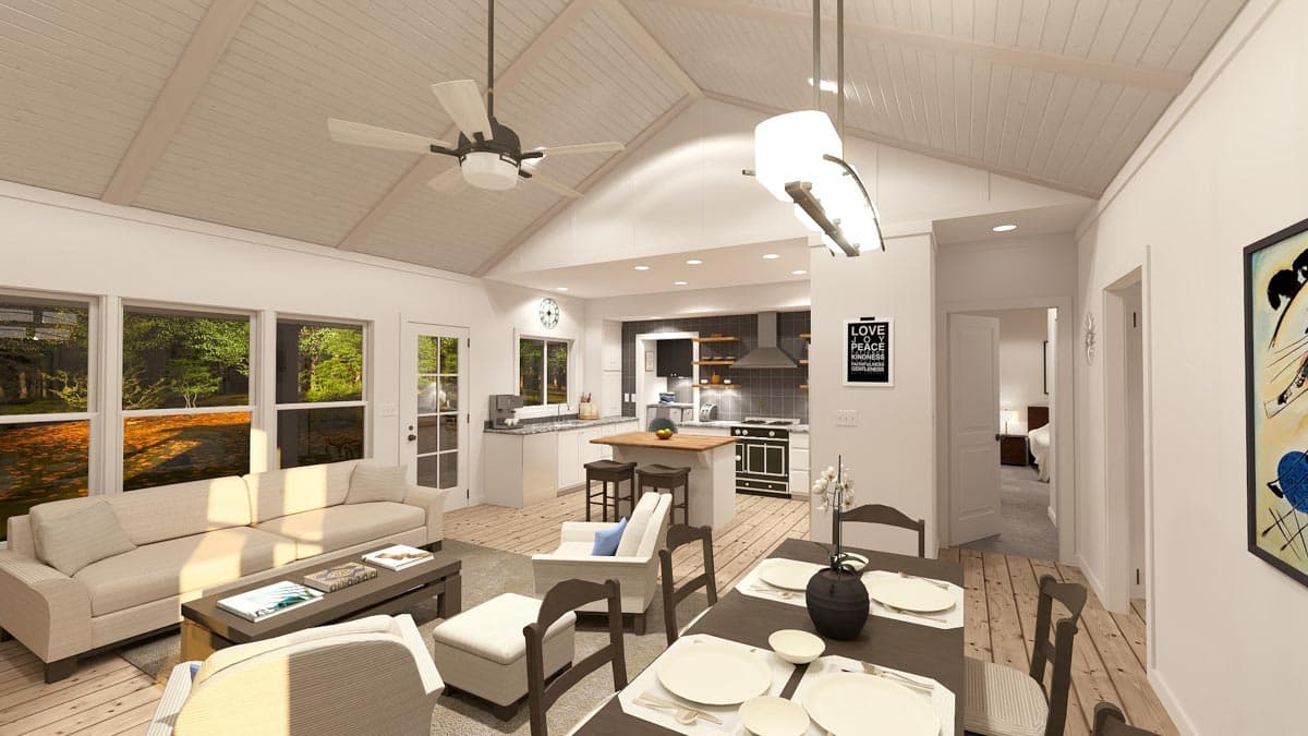 Open concept living, dining, and kitchen area with vaulted ceiling, island, and large windows overlooking outdoors.