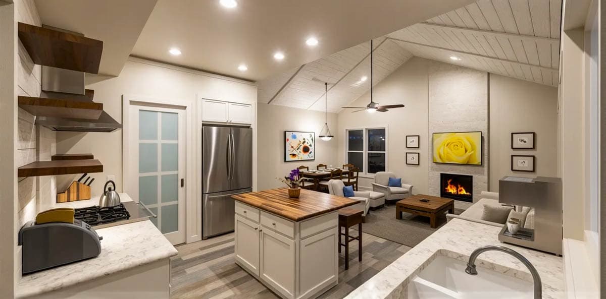 Open-concept living space with kitchen island, fireplace, vaulted ceiling, and dining area.