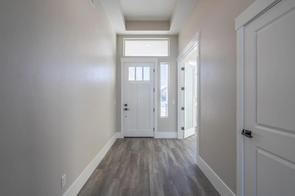 Interior entry hall with white paneled door, sidelight, transom window, and coffered ceiling.