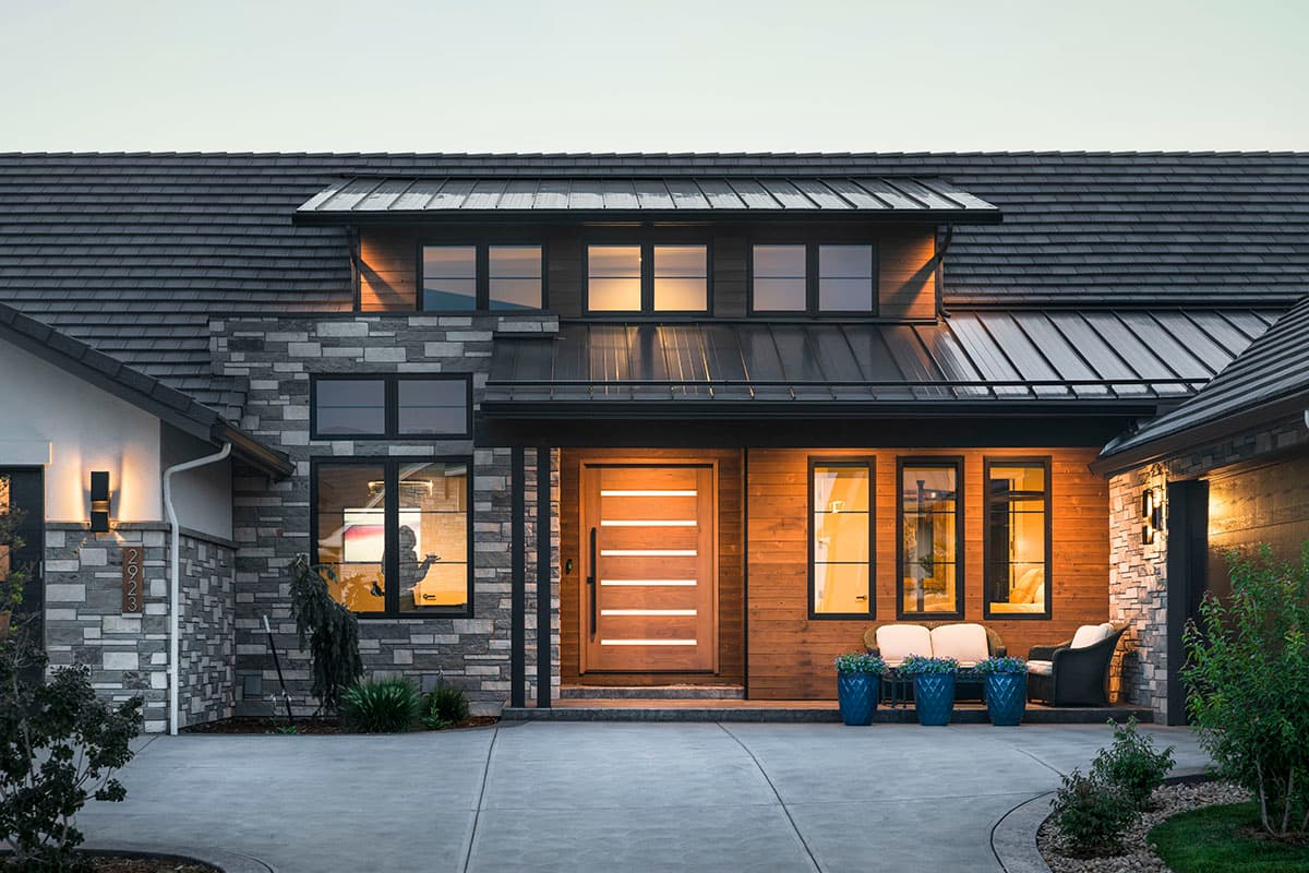 Modern house plan exterior with stone and wood siding, prominent rooflines, and a multi-light front door.