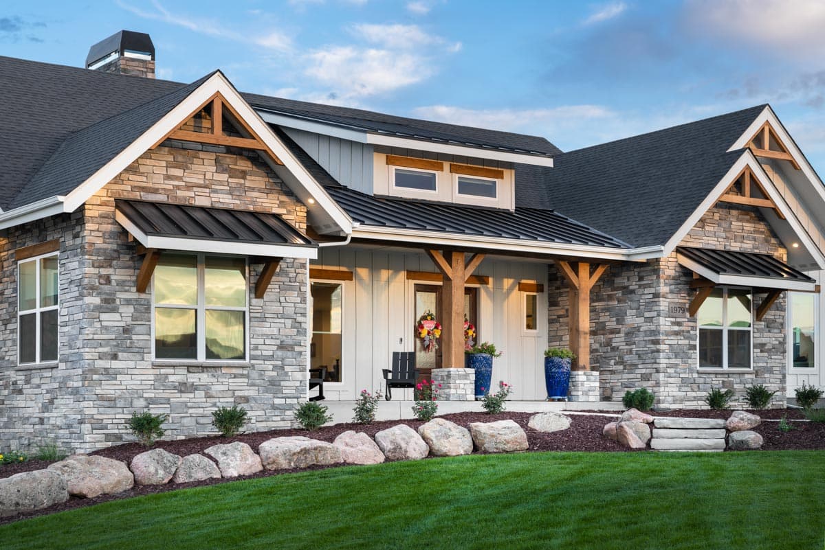 House plan exterior with stone veneer, timber accents, gabled dormers, and covered porch.