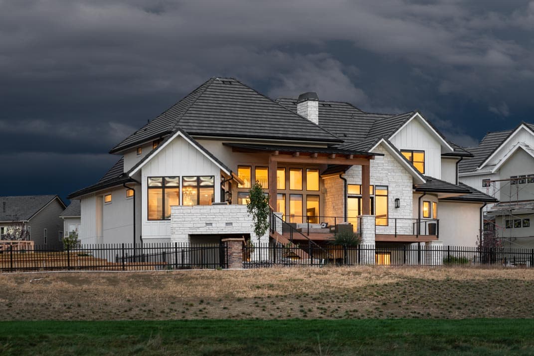 Modern Farmhouse house plan exterior with stone accents, multiple gables, large windows, and a covered deck.