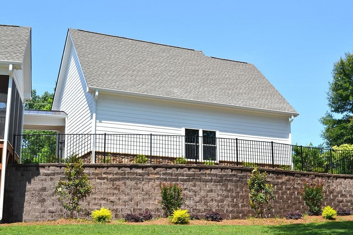 House plan exterior: Contemporary style, one story, white siding, gable roof, attached covered walkway, and a black metal fence.