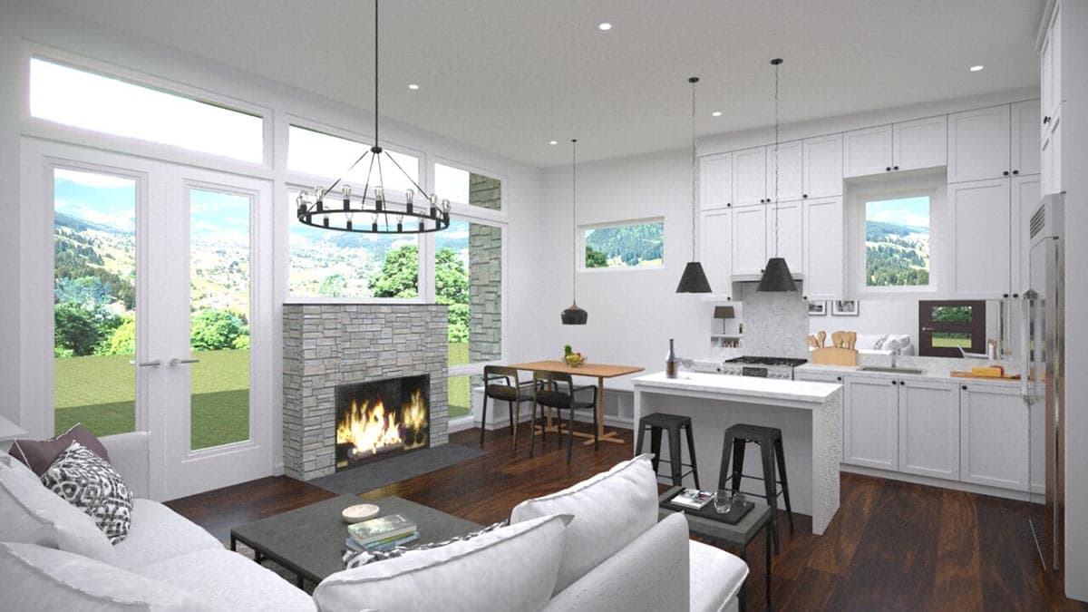Open concept living area with stone fireplace, kitchen island, and large windows overlooking a landscape.