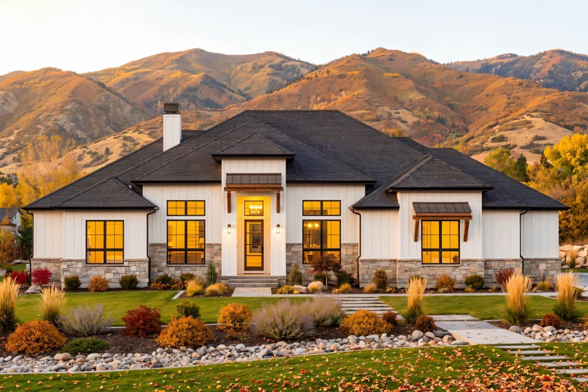 Modern ranch house plan exterior with white board and batten siding, stone base, dark roof, and large windows.