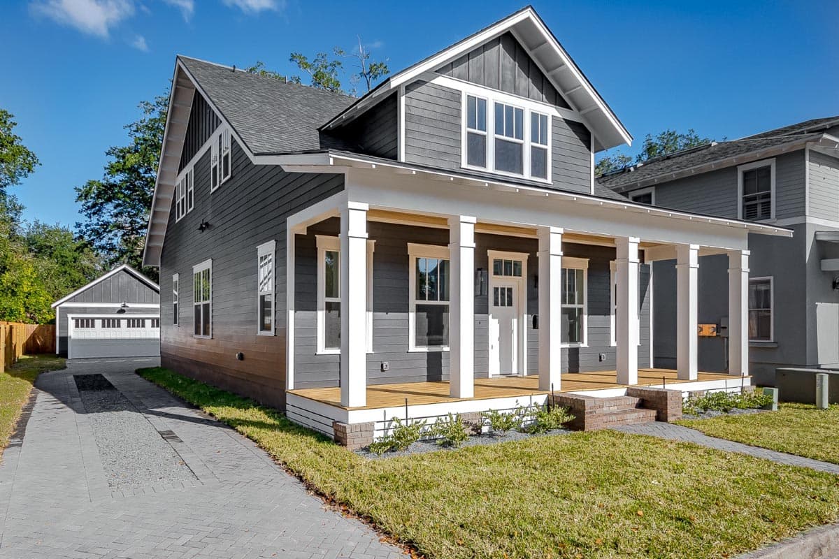 House plan exterior: two-story home with a covered front porch, multiple gables, and a detached garage.