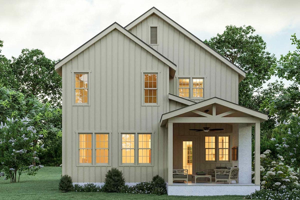 Exterior view of a two-story farmhouse-style home with a covered porch and numerous windows, surrounded by lush trees and landscaping.