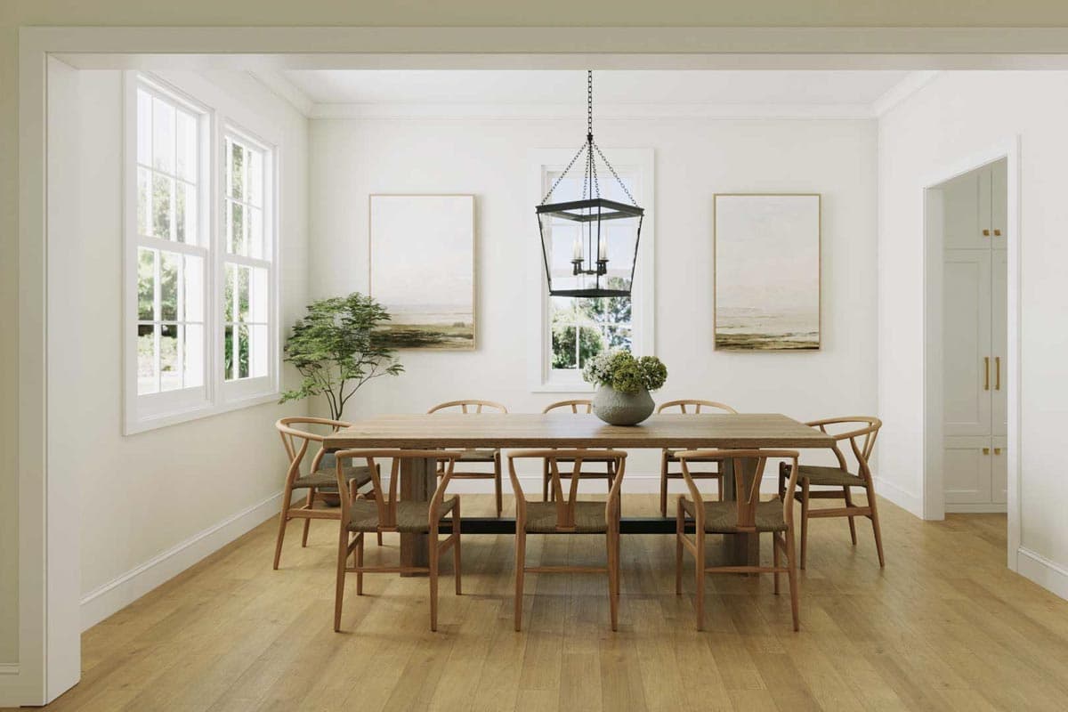 A dining room with a large wooden table and chairs, a chandelier, and two landscape paintings, creating a warm, inviting atmosphere.