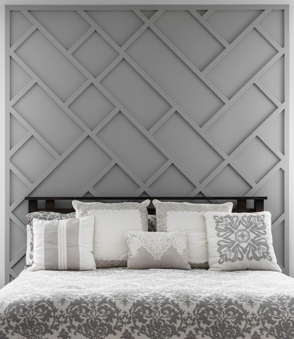 Bedroom with a gray geometric wall, dark wood headboard, and decorative pillows on a patterned bedspread, creating a tranquil atmosphere.