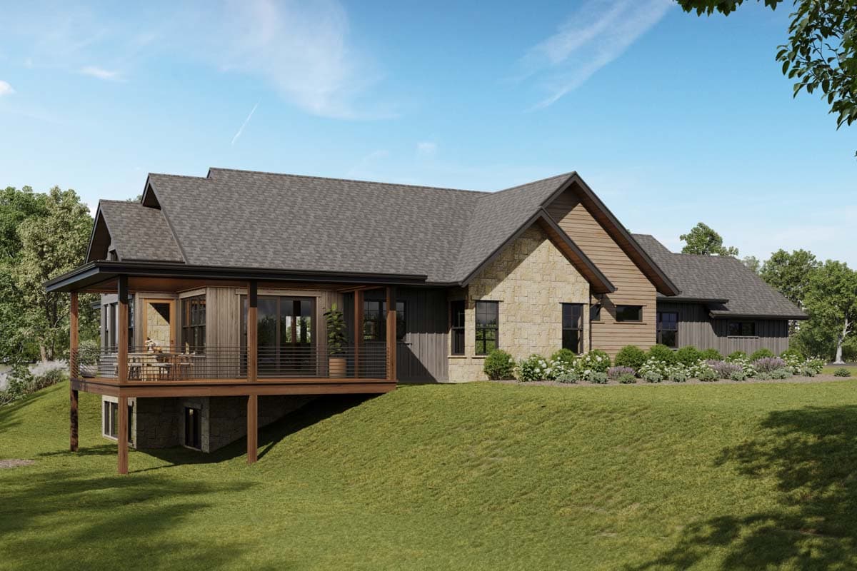 A modern, single-story house featuring a stone facade and wooden accents, with a deck overlooking a grassy hill, under a blue sky.