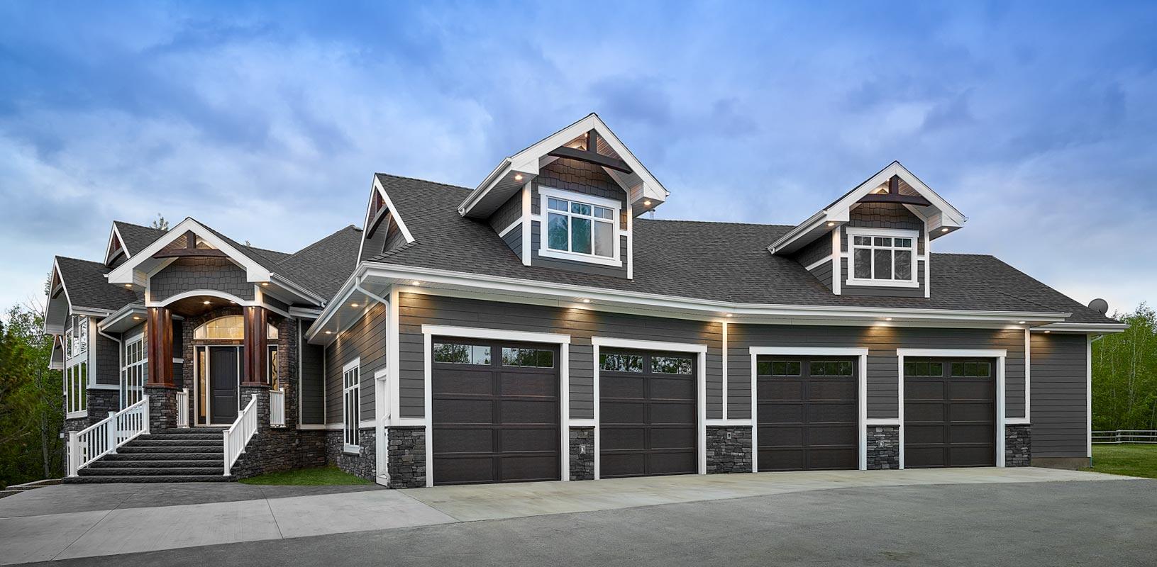 House plan exterior with a prominent arched entryway, four-car garage, multiple gables, and stone and shingle accents.