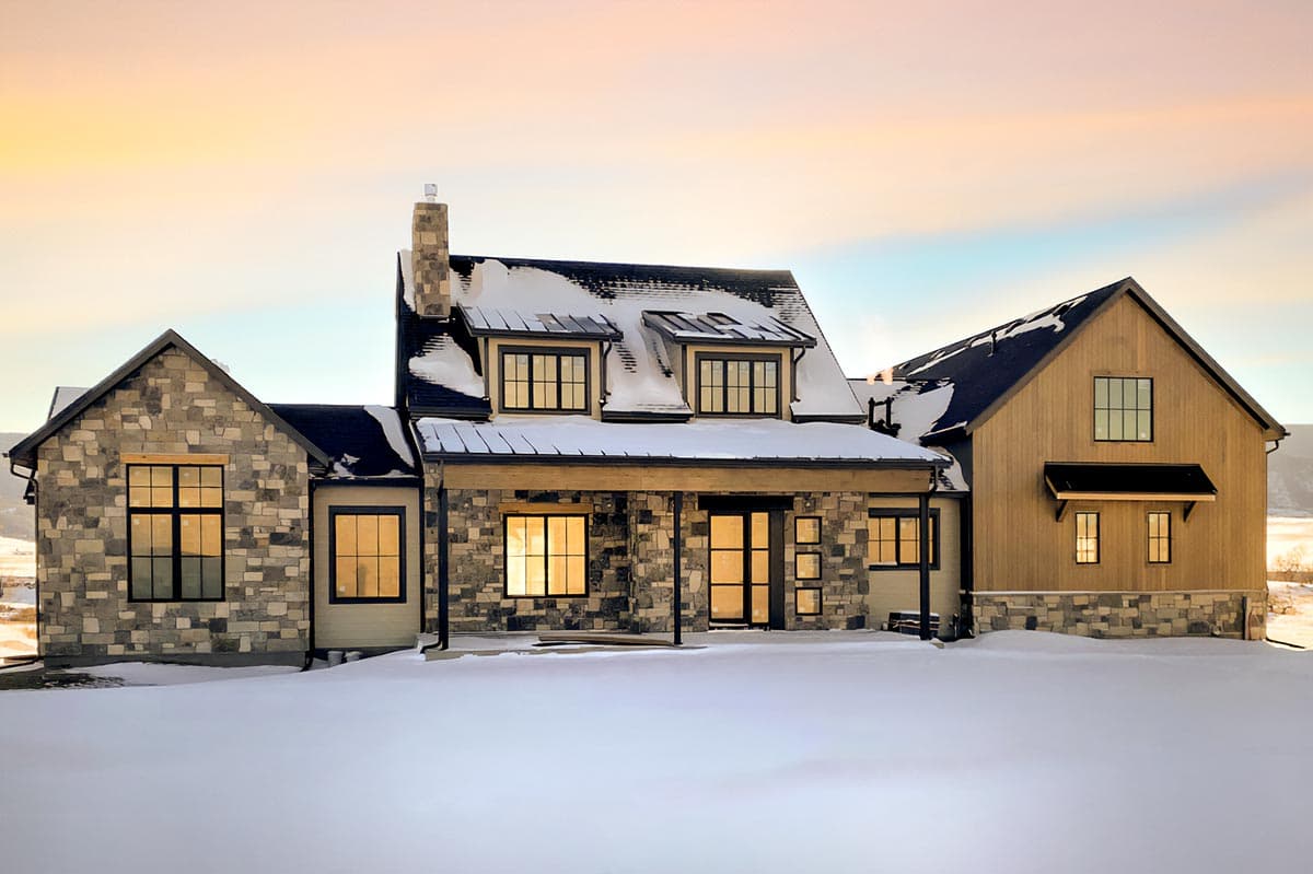 House plan exterior with stone and wood siding, gabled roof, and multiple dormers. Includes a covered porch, and a chimney.