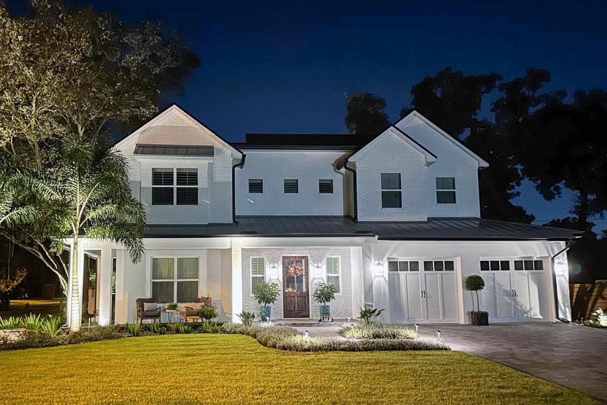 Modern Farmhouse house plan exterior with two stories, white brick, metal roof, and a three-car garage.