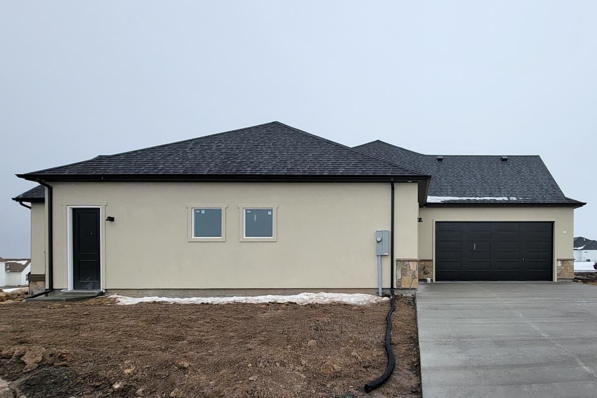 House plan exterior, single-story, stucco finish, dark garage door, dark entry door, gabled roof.