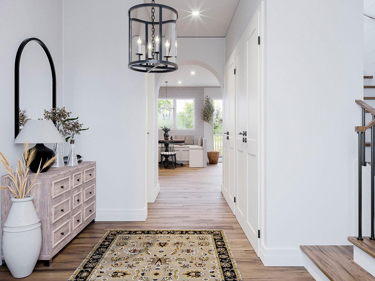 Interior view of a hallway with an arched entryway to a living area, double doors, and staircase.