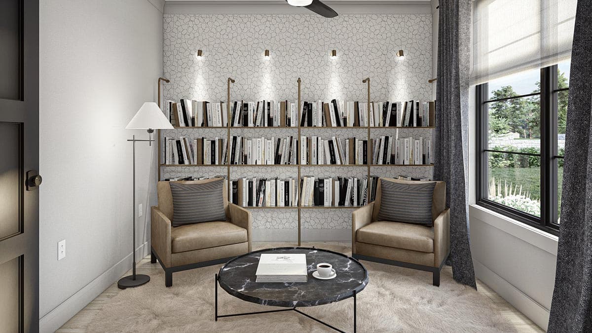 Interior view of a den featuring a wall of bookshelves, two armchairs, a round coffee table, and a large window with an exterior view.