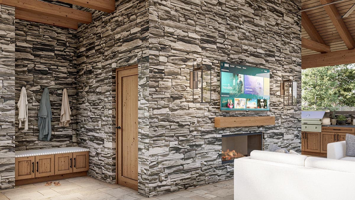 An outdoor living space with a stone fireplace, TV, and seating area. Wooden elements like beams, doors, and a bench complement the stone walls.