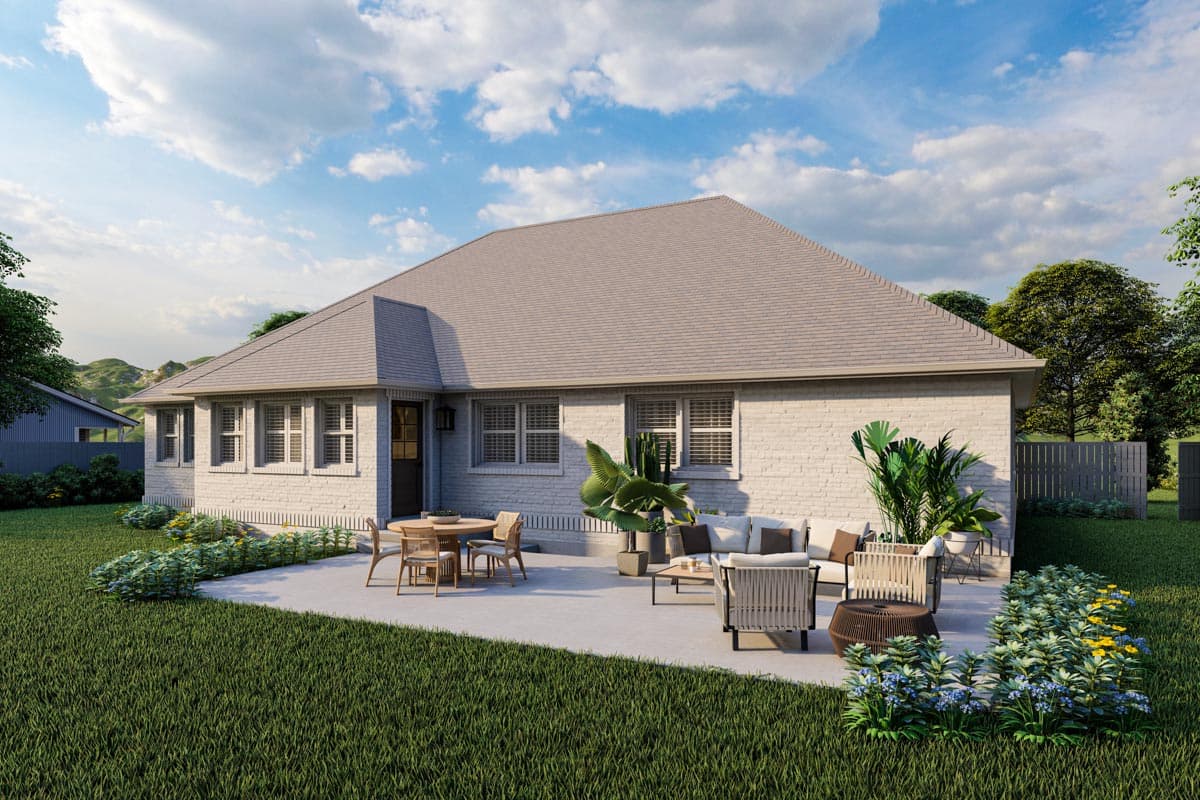 House plan exterior of a one-story brick home with a hip roof, multiple gables, and a patio with outdoor furniture.
