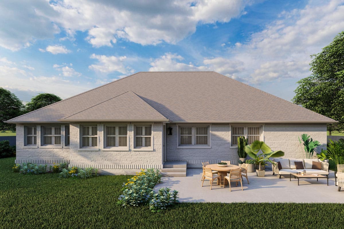 House plan exterior rendering of a single-story home with white brick facade, multiple windows, and a large, paved patio with outdoor furniture.