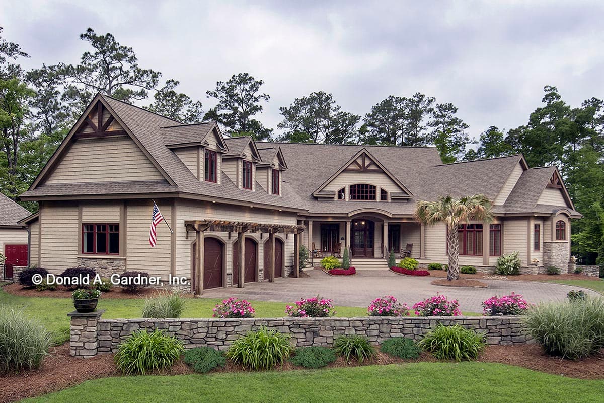 House plan exterior with Craftsman style. Features include multiple gables, dormers, and a pergola-covered garage with arched doors. Two-story.