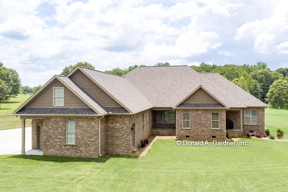 House plan exterior: One-story brick home with shingle siding, prominent gables, dormer window, and covered front porch.