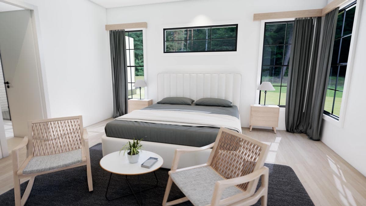 A modern bedroom with a large bed, two woven chairs, and a small table. Windows offer a view of trees outside with neutral-toned decor.