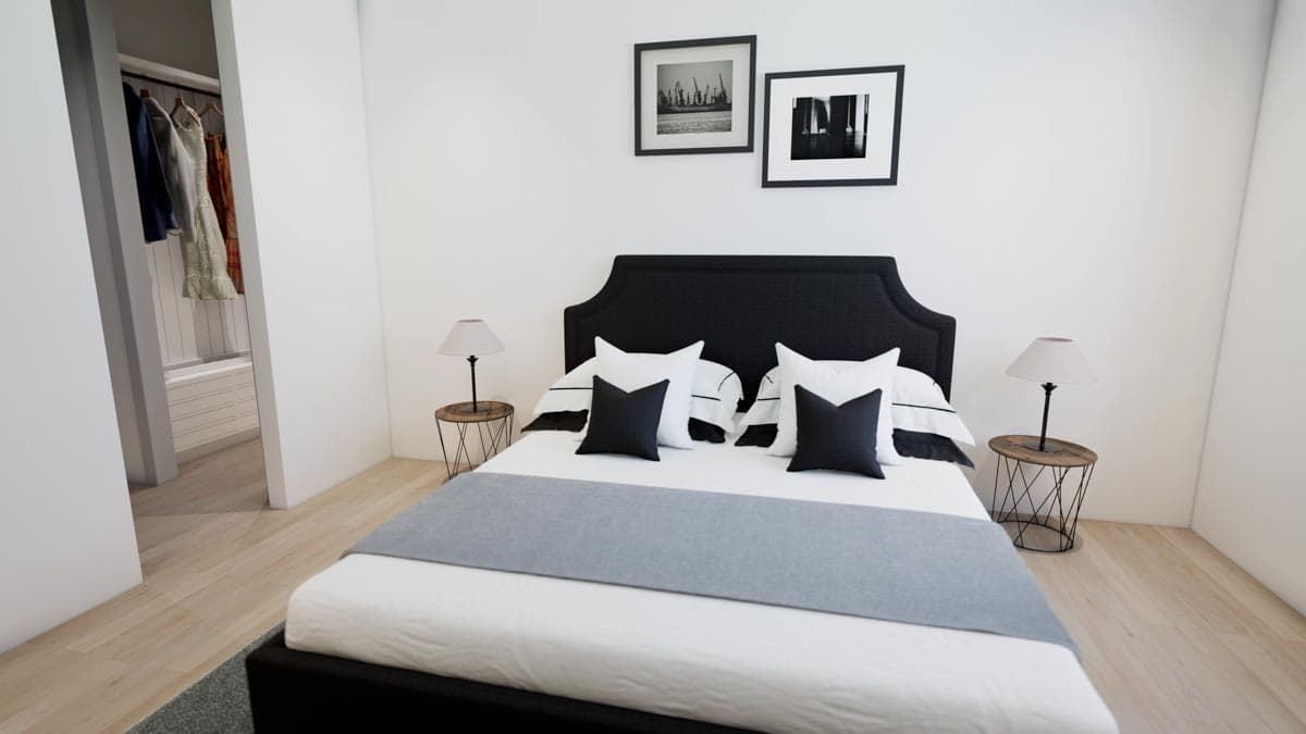Modern bedroom with a black headboard, white bedding, and black accent pillows. Two framed pictures hang above the bed. A walk-in closet is visible.