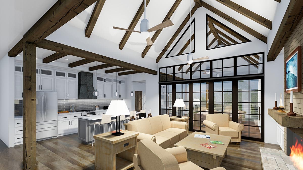 Spacious open-concept living area with vaulted ceiling, exposed wooden beams, and a view of the kitchen and outside through large glass doors.