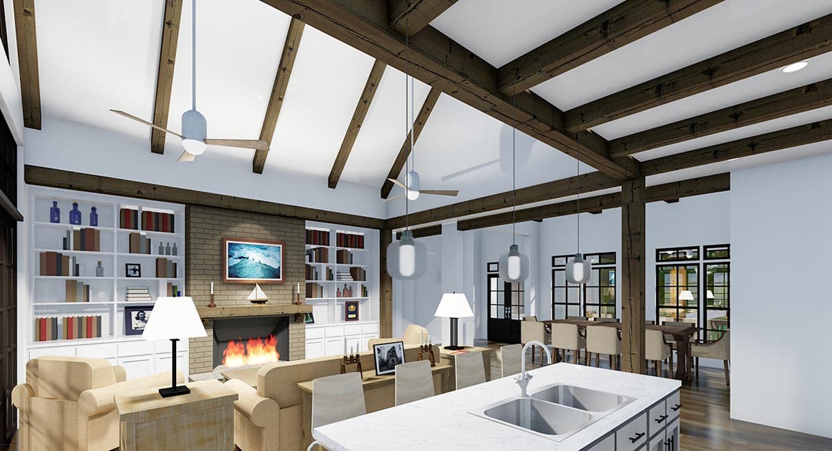 Spacious, open-plan living space with exposed wooden beams, a fireplace, bookshelves, and a kitchen island with seating. Dining area visible.