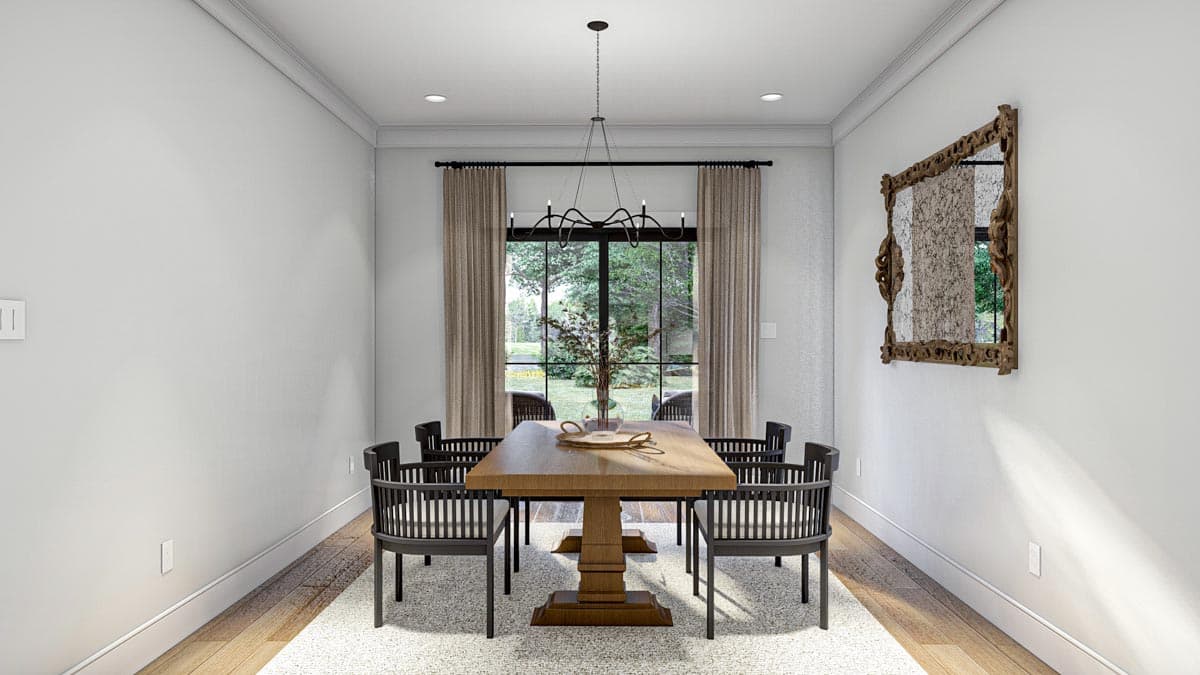Dining room with pedestal table, chairs, chandelier, large window overlooking trees, and ornate mirror.