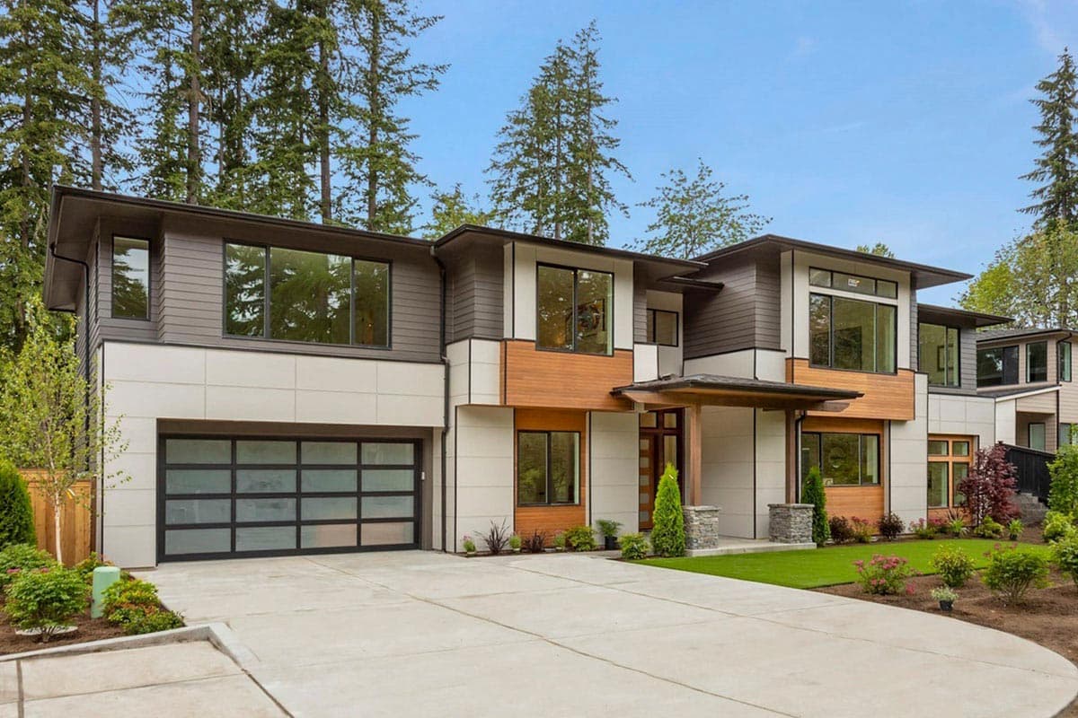 Modern two-story house plan exterior with horizontal siding, wood accents, multiple gables, and a frosted glass garage door.