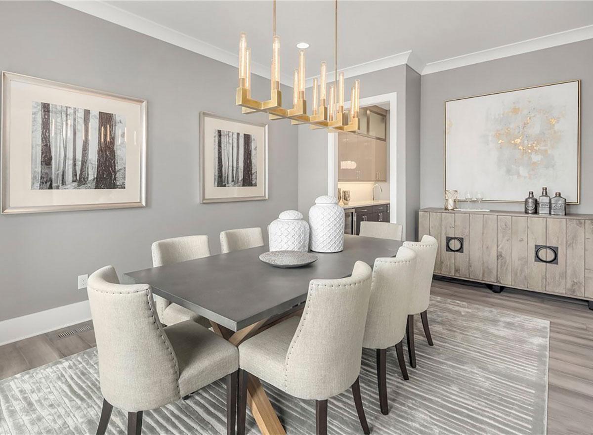 Dining room with gray table, upholstered chairs, contemporary chandelier, and modern sideboard.