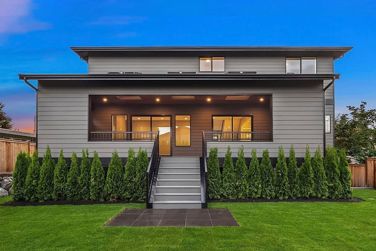 Modern two-story house plan exterior with a covered balcony, horizontal siding, and flat roof.