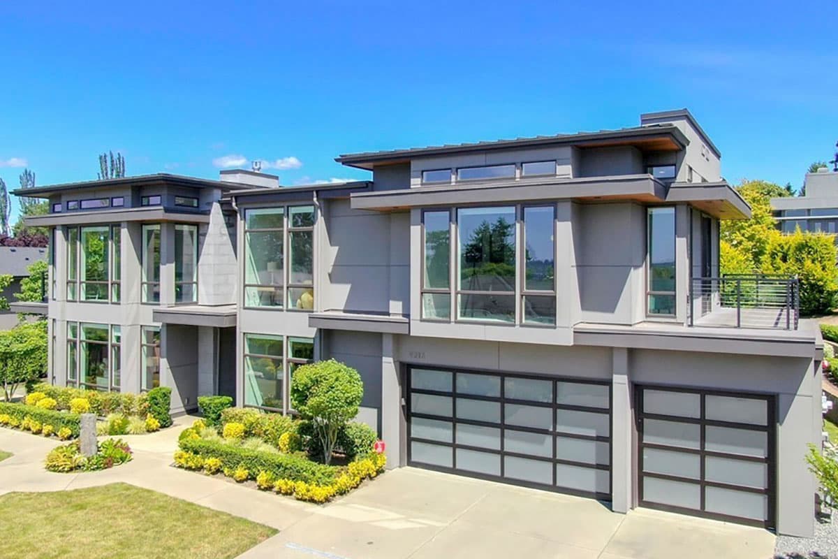 Modern house plan exterior, two stories, featuring stacked volumes, extensive glazing, flat rooflines, and a multi-car garage.