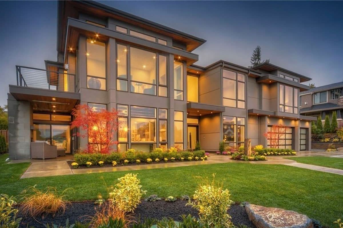 Modern house plan exterior featuring multiple stories, cantilevered balcony, extensive glass windows, and a glass-paneled garage door.