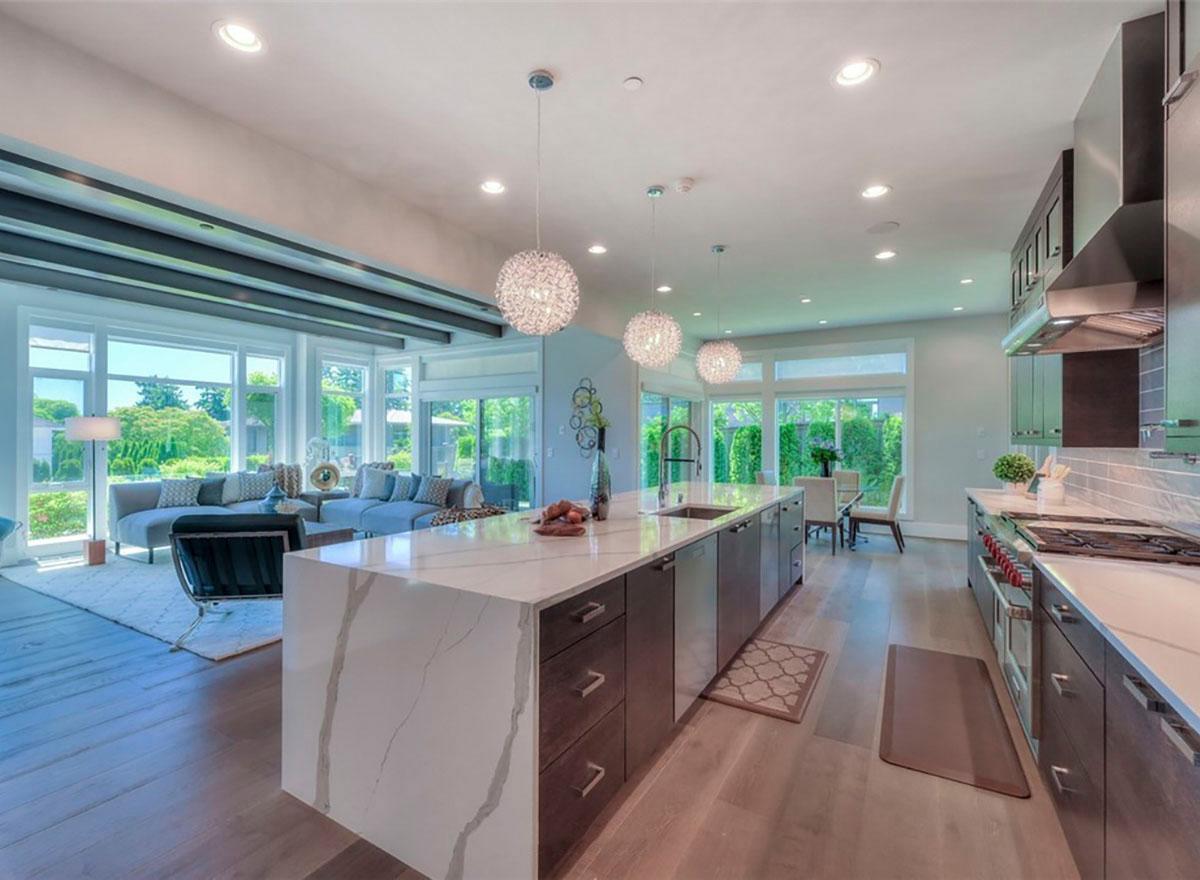 Open concept kitchen and great room with large island, vaulted ceiling, and extensive windows.