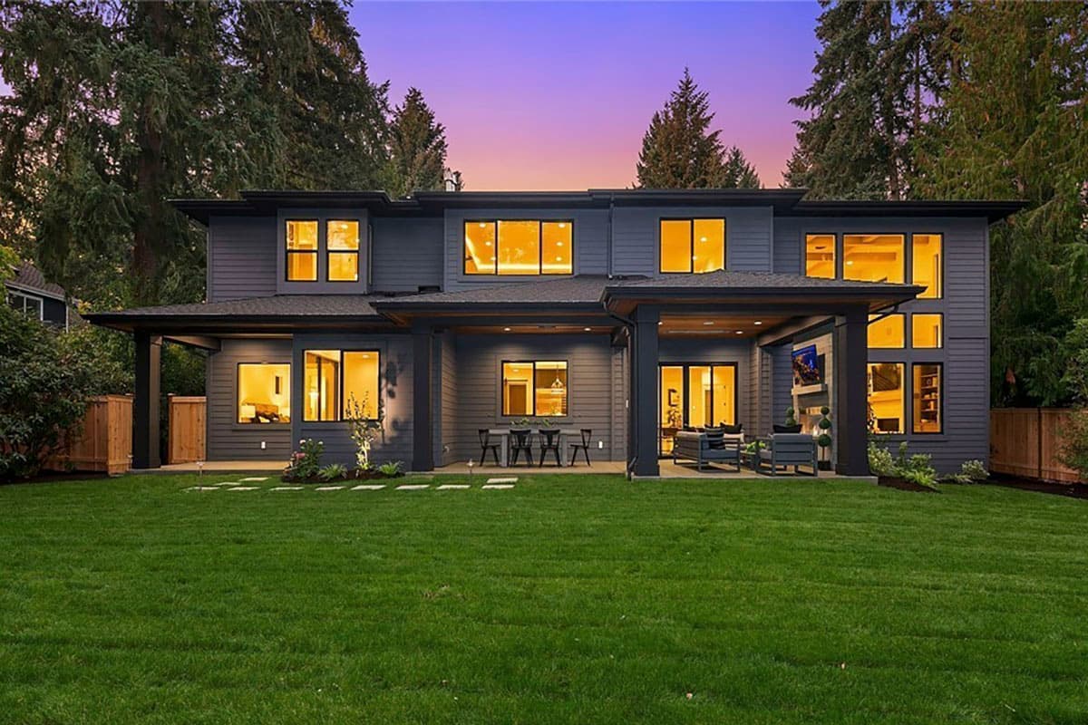 Modern house plan exterior with dark siding, multiple levels, flat rooflines, large windows, and covered patios.