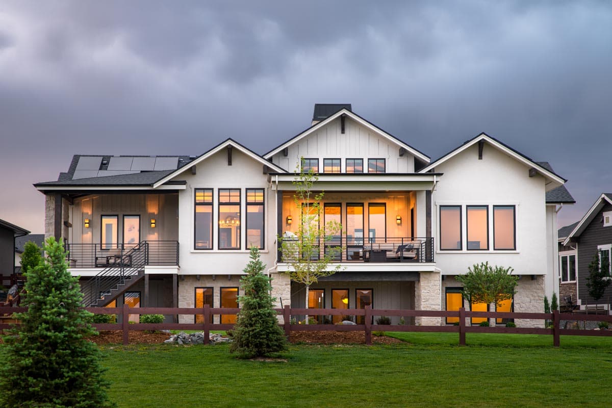 Modern Farmhouse house plan exterior with multiple gables, balconies, large windows, and solar panels.