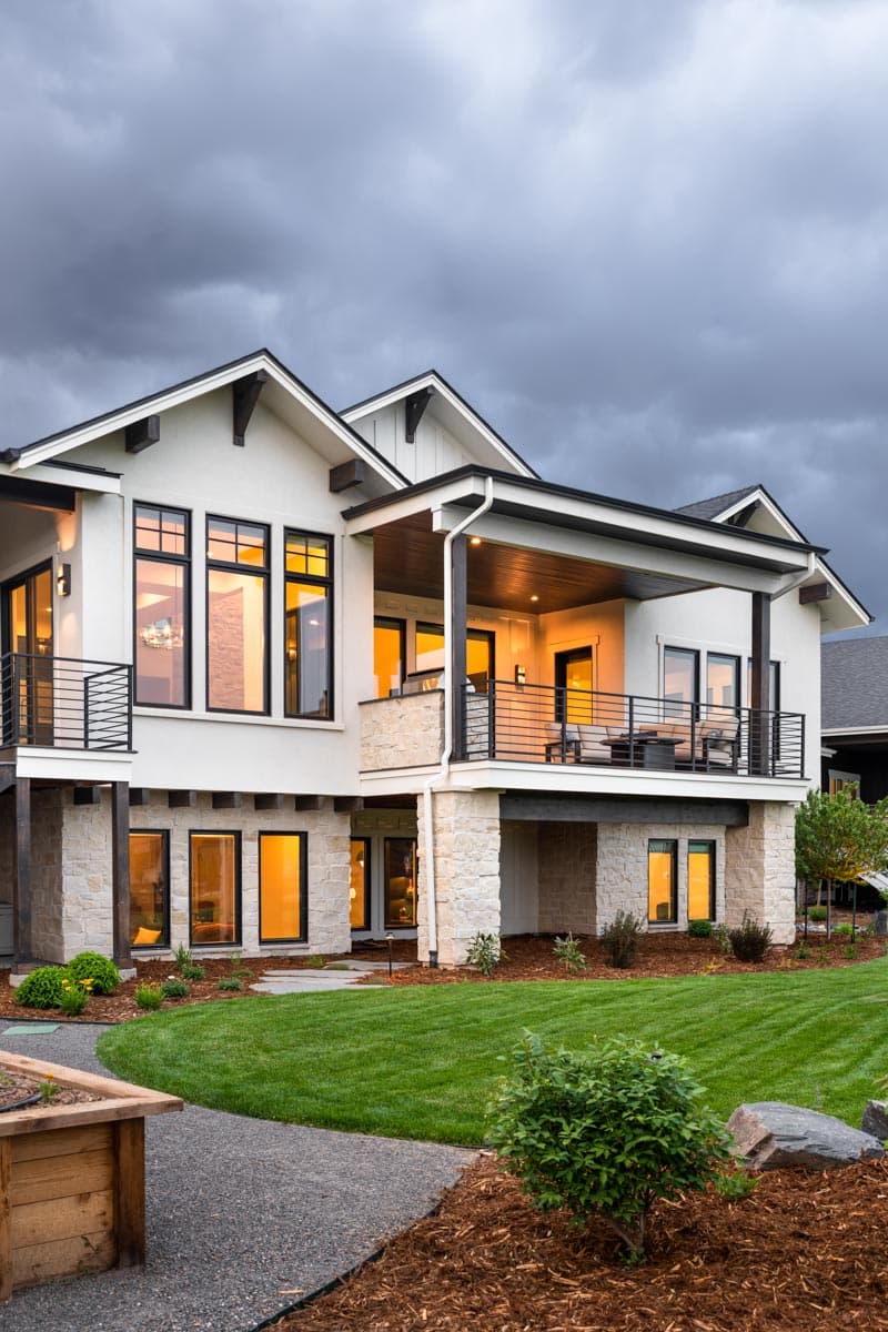 Modern Farmhouse house plan exterior with stone base, gables, covered balcony, and large windows.