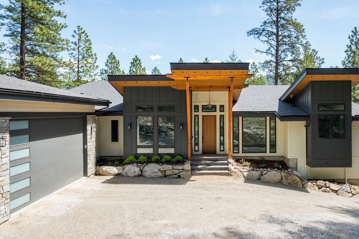 Modern house plan exterior with a multi-level roofline, wood-accented entryway, large windows, and attached garage.