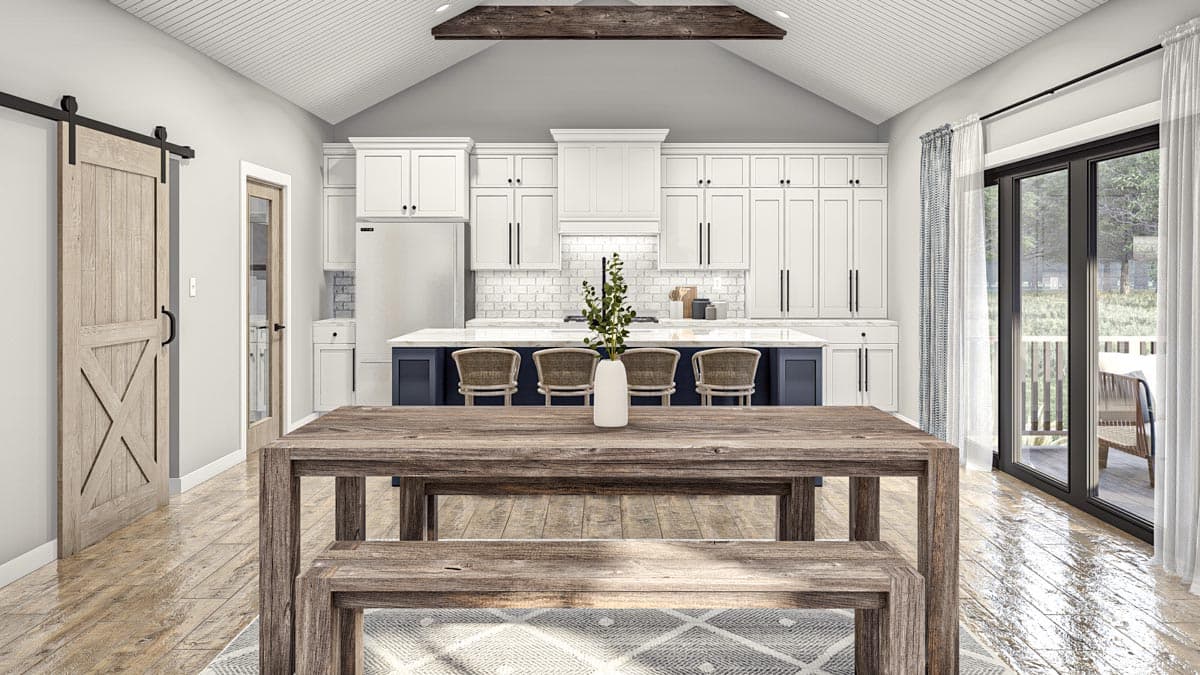 Kitchen and dining area with vaulted ceiling, white cabinetry, island with seating, and barn door.